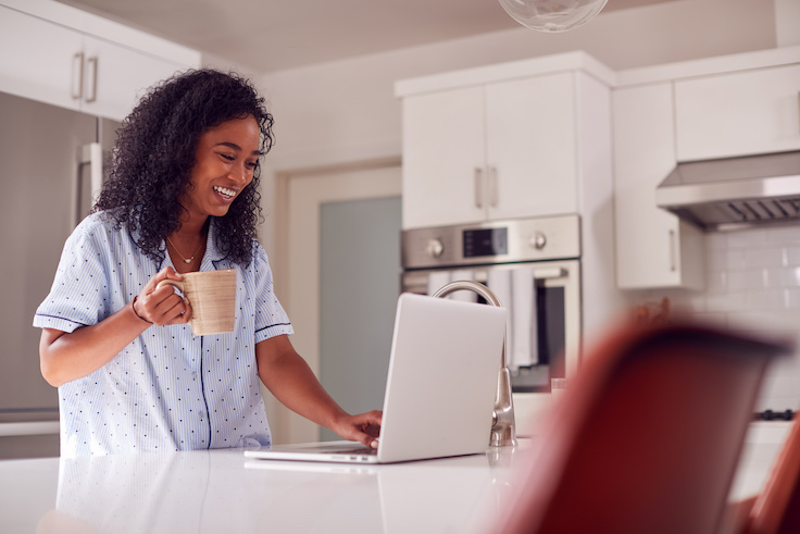 Woman with laptop in her kitchen wearing PJs
