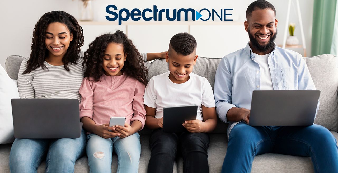 Happy diverse family sitting on couch with their devices