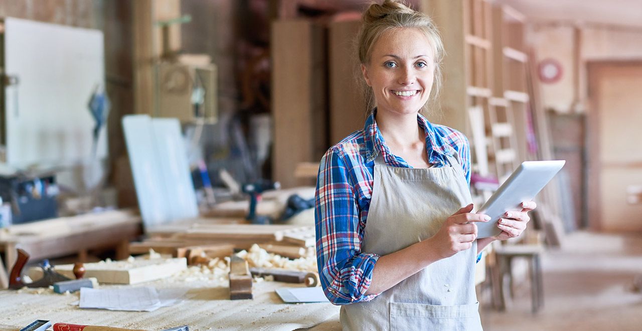 Female small business owner holding a tablet in her store smiling