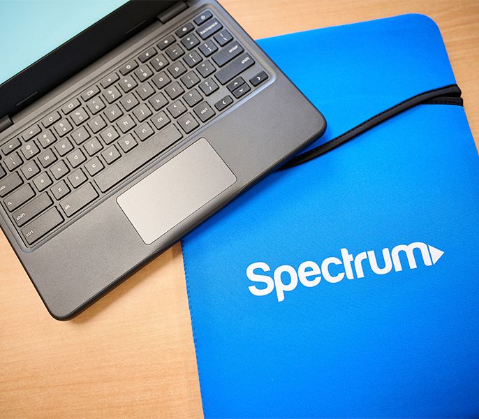 Laptops sitting in an empty computer lab with mousepad with Spectrum logo