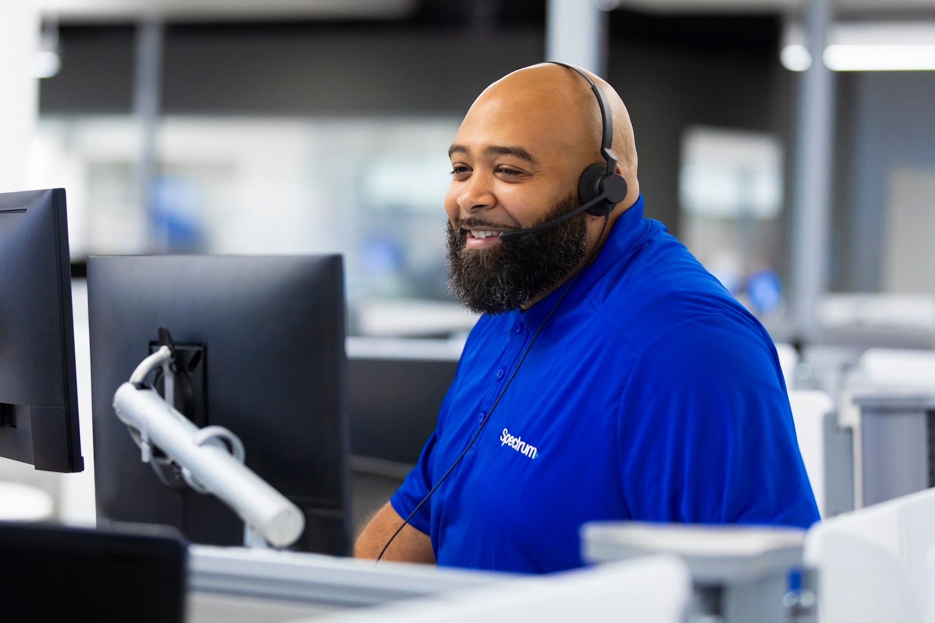 A Spectrum call center agent with headset on helping a customer