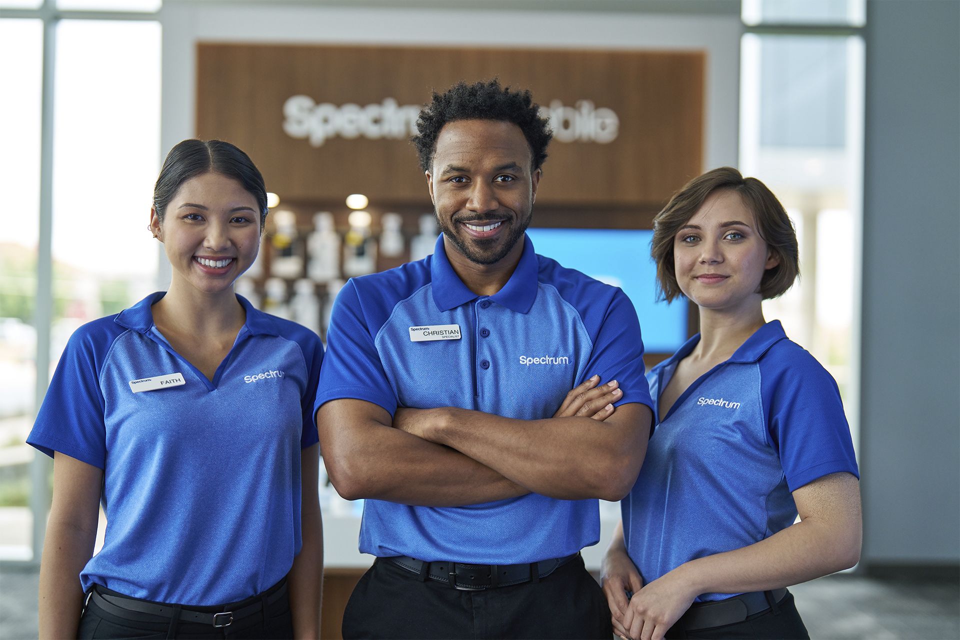 Three Spectrum employees smiling in a Spectrum Mobile store